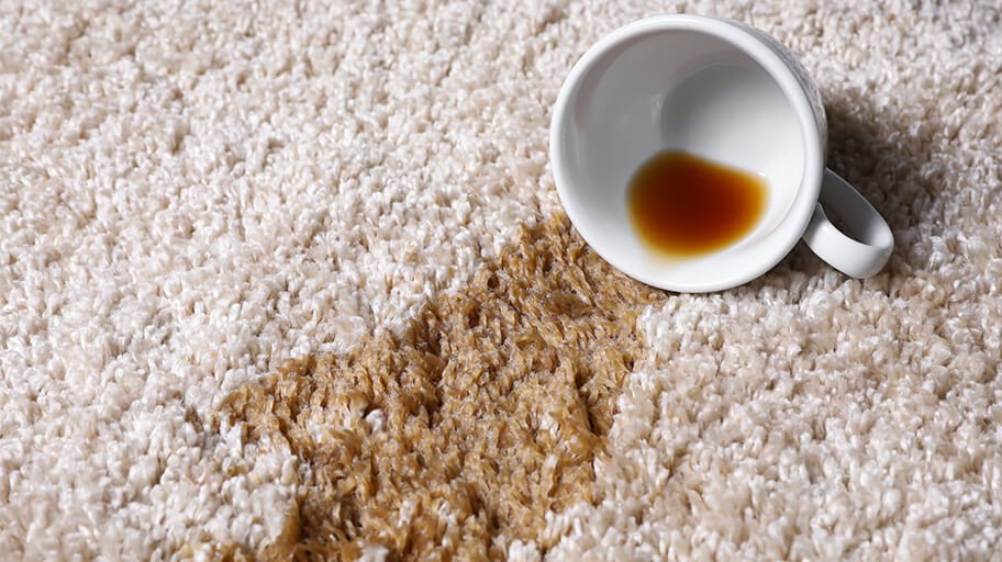 Overturned cup spilling tea on a carpet
