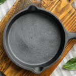 Photo of a clean cast iron pan on a wooden board.