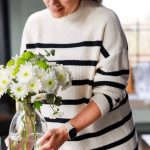 Woman modern homemaker at home arranging white flowers in a glass vase