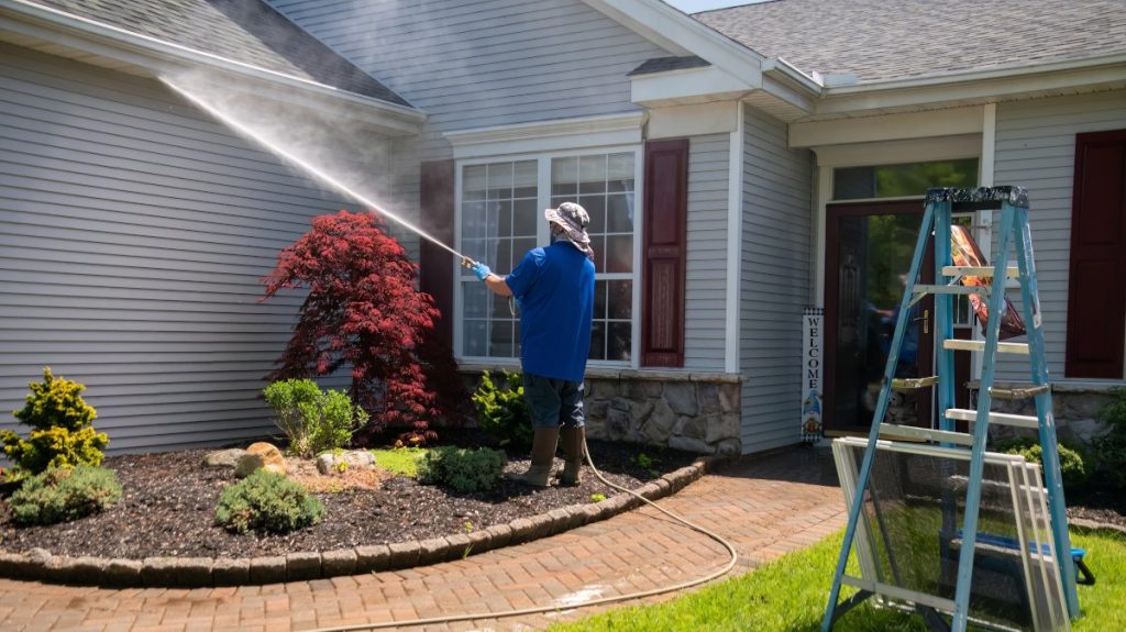 Contractor pressure washing the exterior of a beautiful house