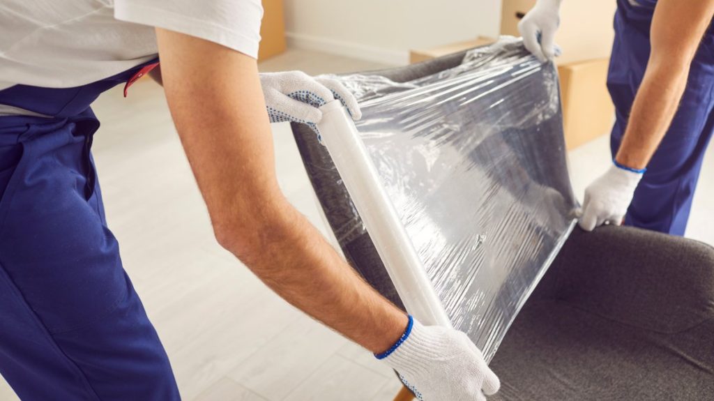 Two removalists packaging furniture, preparing for moving