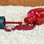 Spilled red nail polish on white carpet