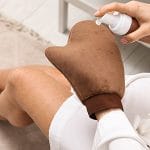 Woman spraying fake tan on glove