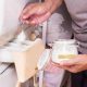 Man pouring baking soda in washing machine to get rid of the bad smell naturally.
